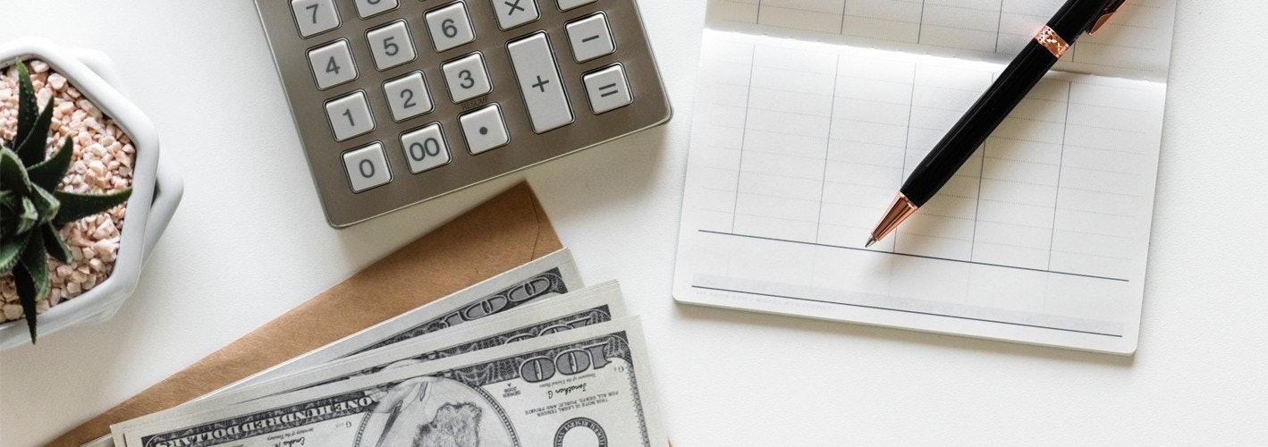calculator, checkbook and some money sitting on a table